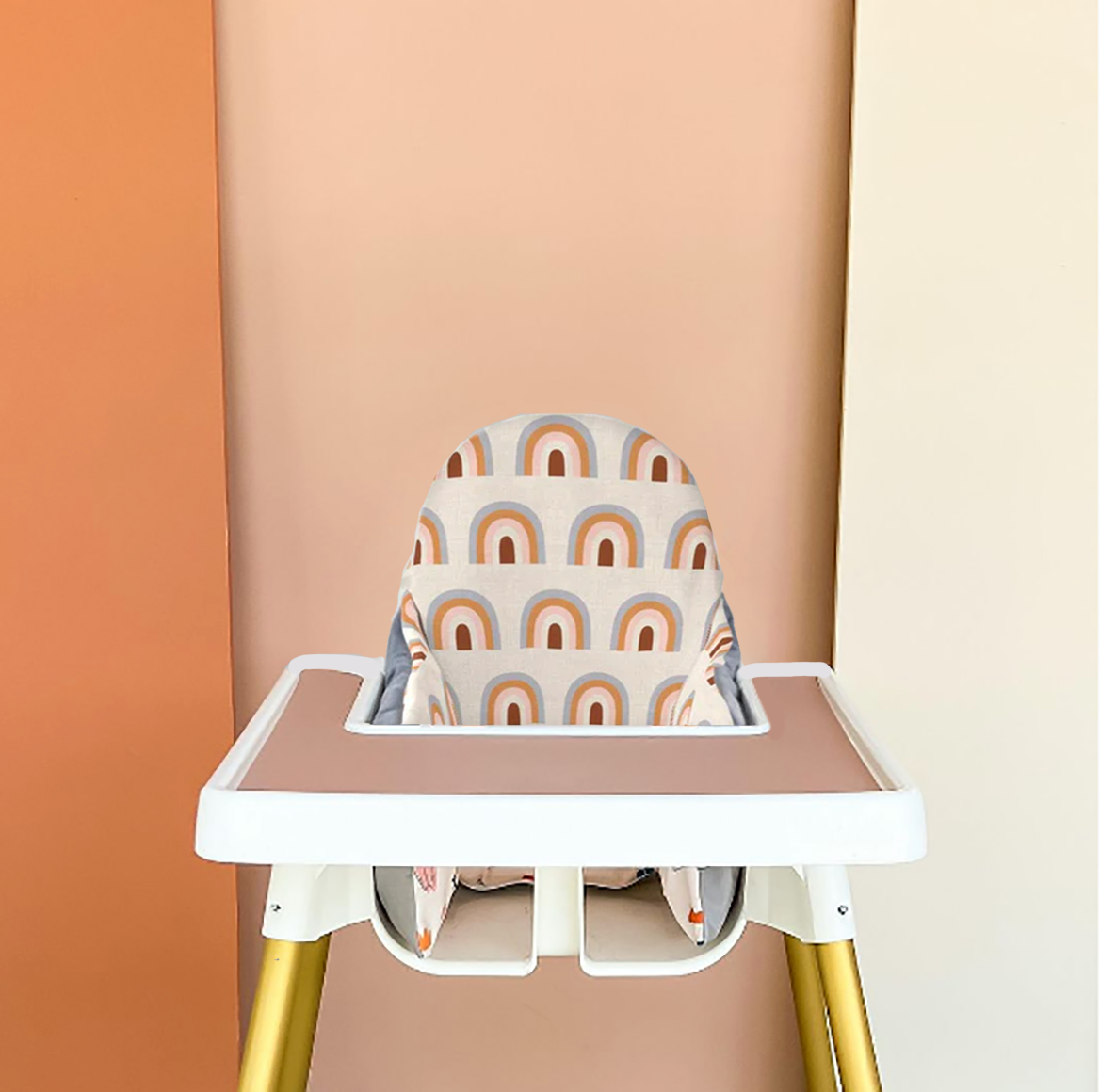 photo of a Ikea Antilop highchair with a pink silicone mat on the tray, a Yeah Baby Goods cushion cover on the cushion and gold toned wraps on the legs. Brightly coloured earth toned blush panels are in the background